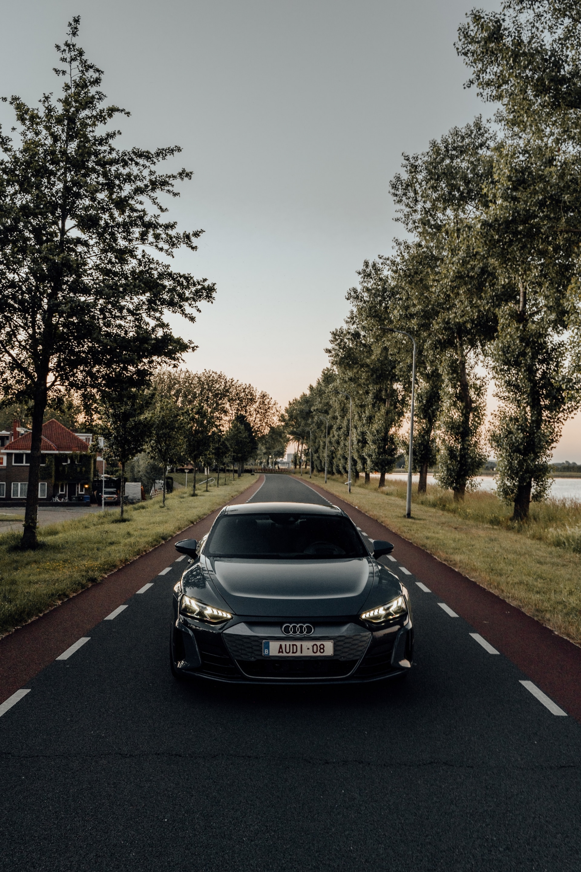 Audi Etron GT electric sports car, driving down a tree-lined street