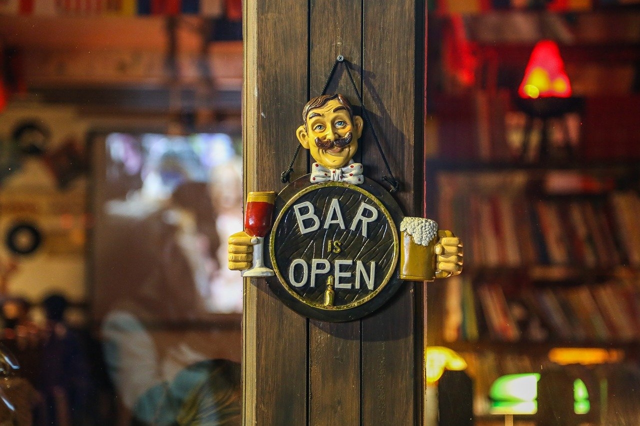 Closeup of a carved sign hanging on a door that reads Bar is Open