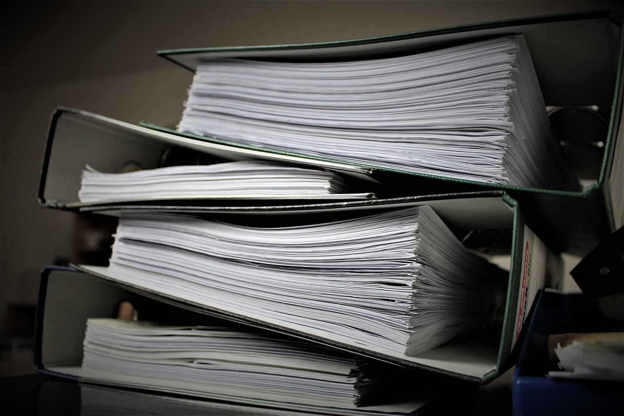 A stack of four large binders, each full of paper