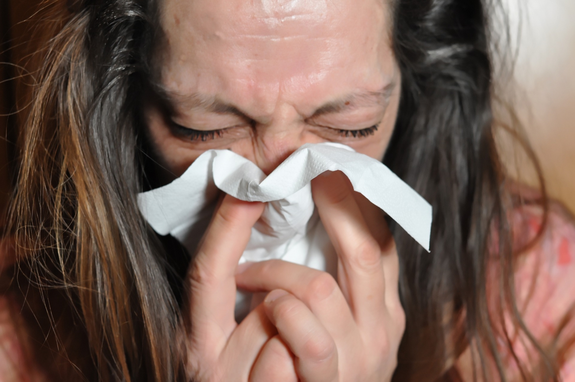 Woman blowing her nose into a tissue