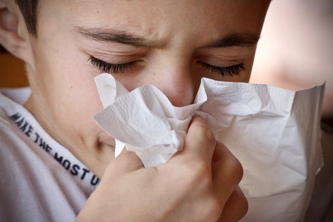 Young boy blowing his nose with a tissue