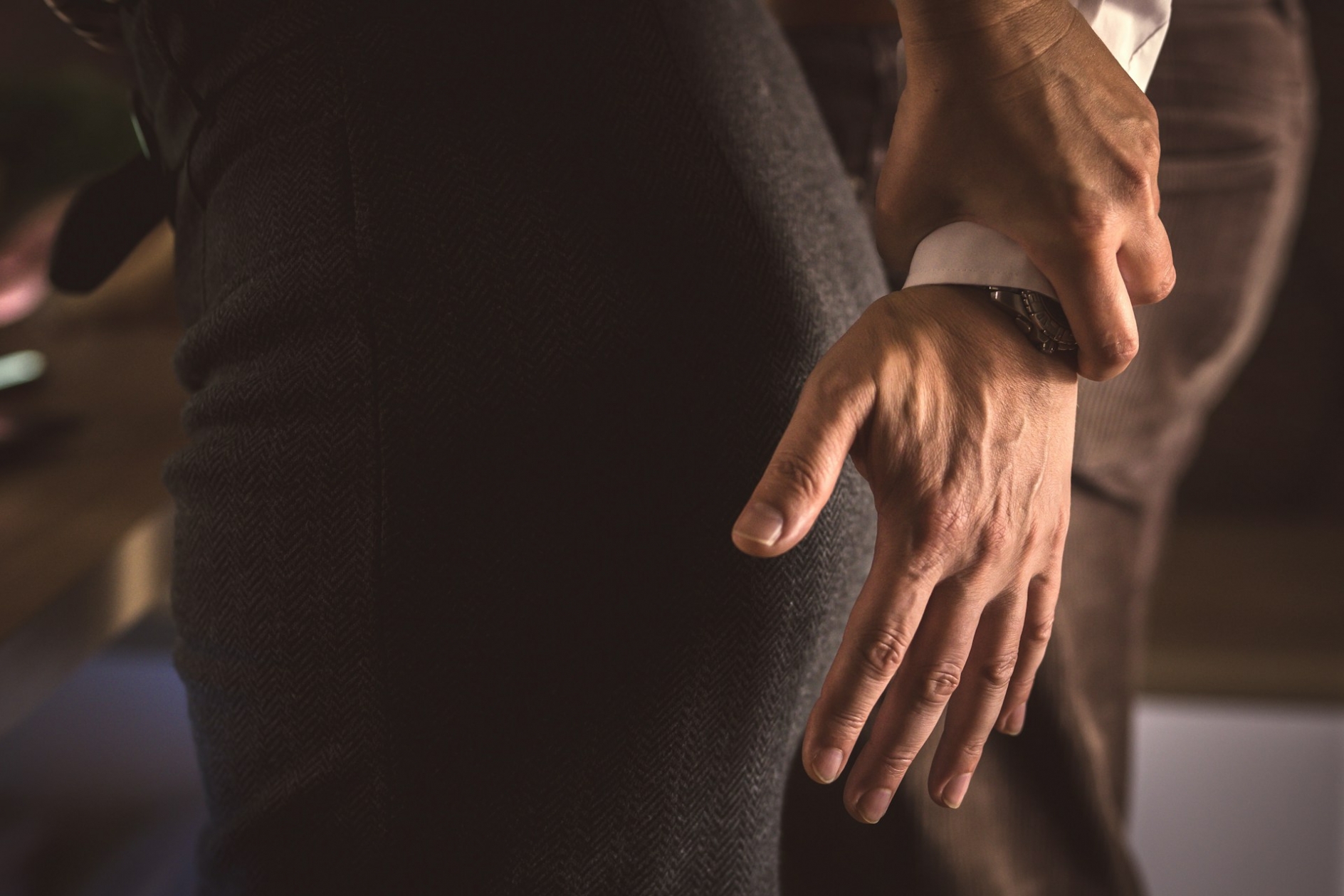 A woman holding back the hand of a man who's trying to grab her butt
