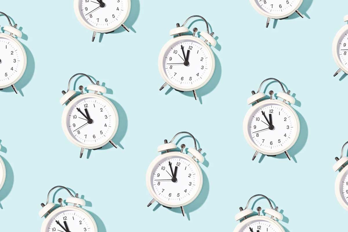 An array of white alarm clocks on a light-blue background