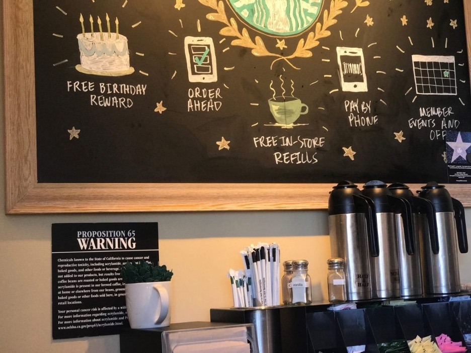 Photo of a Prop 65 warning sign, hanging on the wall of a coffee shop