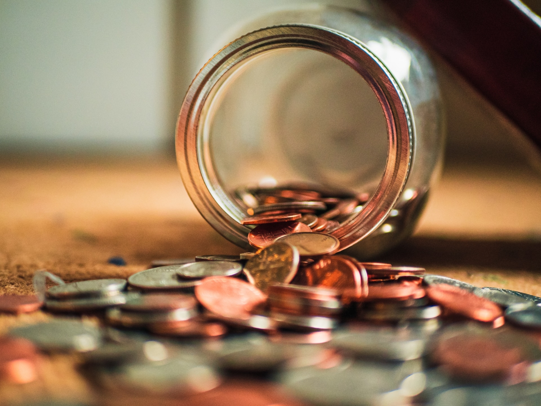 Glass jar on the floor with coins spilling out