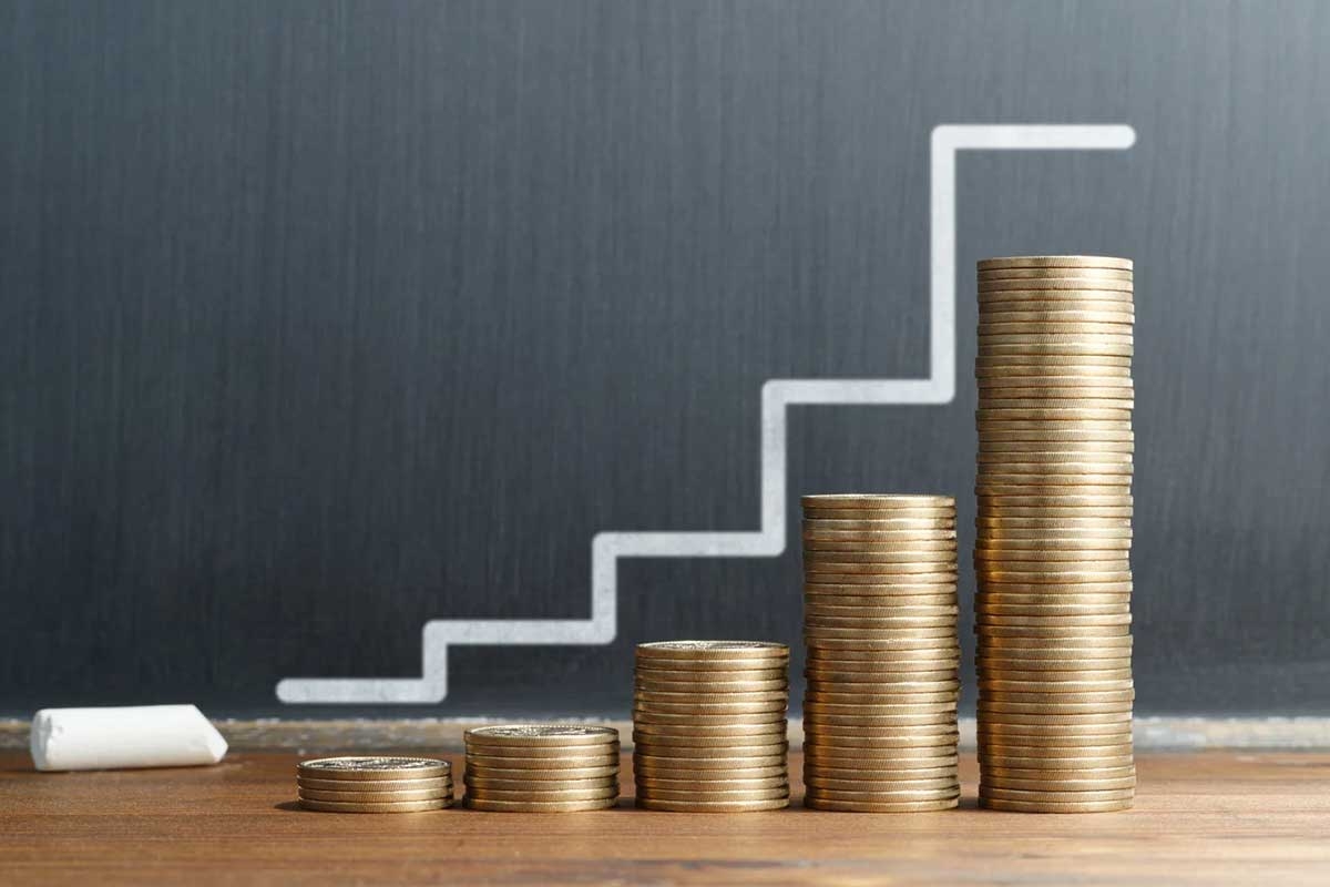 Five progressively higher stacks of coins, with a stair-step line drawn above them in white chalk