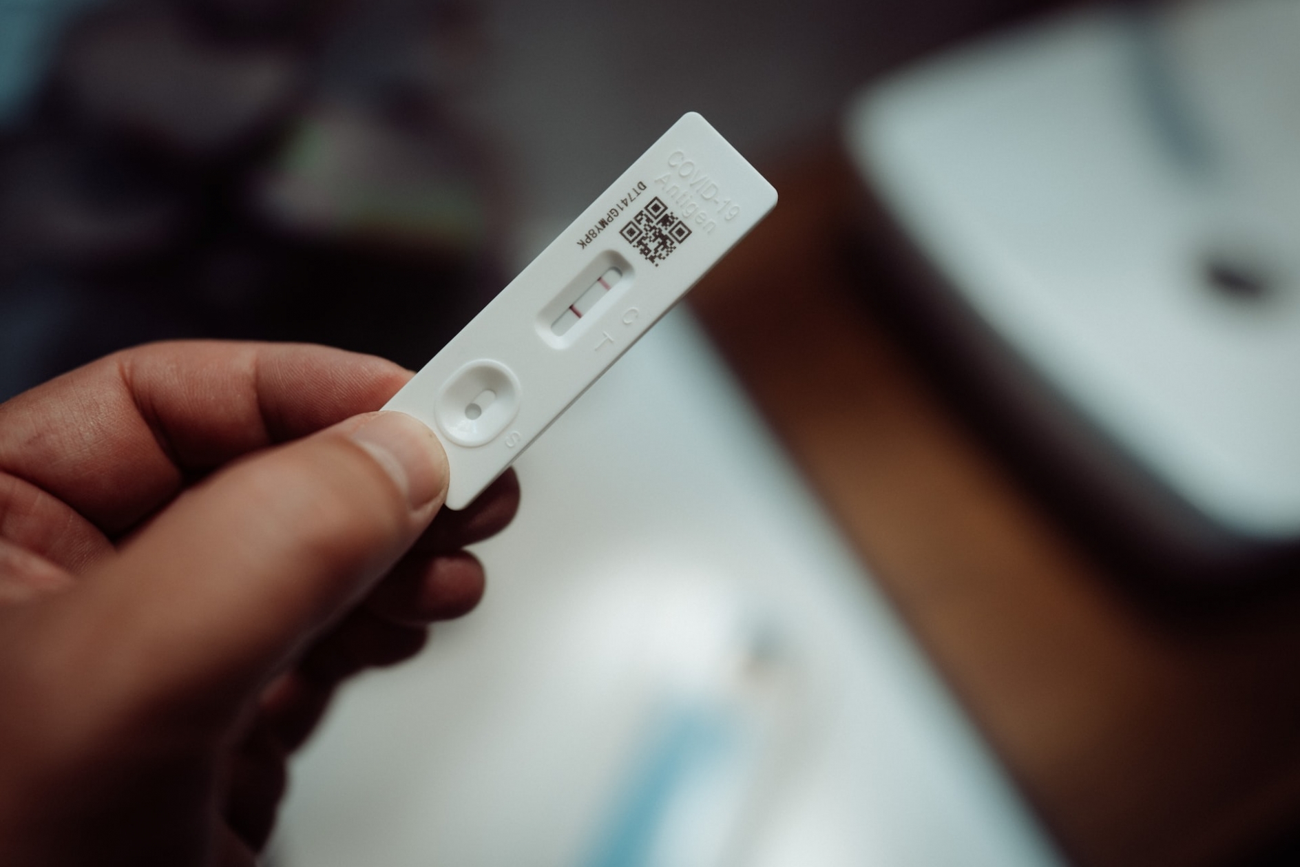 Closeup photo of a hand holding a positive COVID-19 antigen test