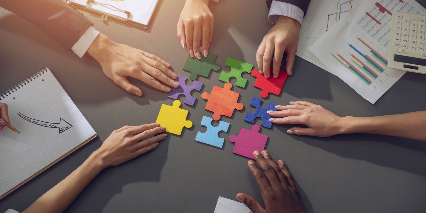 Diverse business people collaborating to put puzzle pieces together