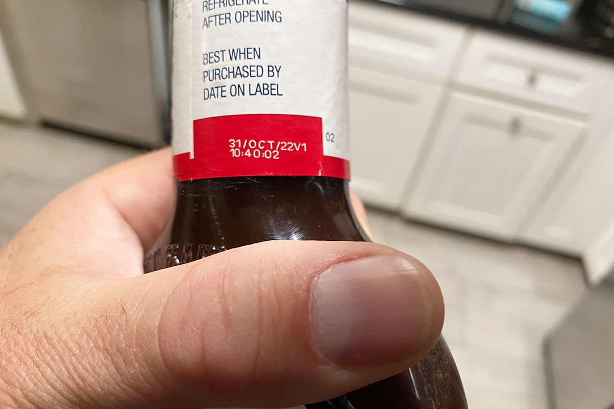 Hand holding a bottle with a best buy date of October 31, 2022