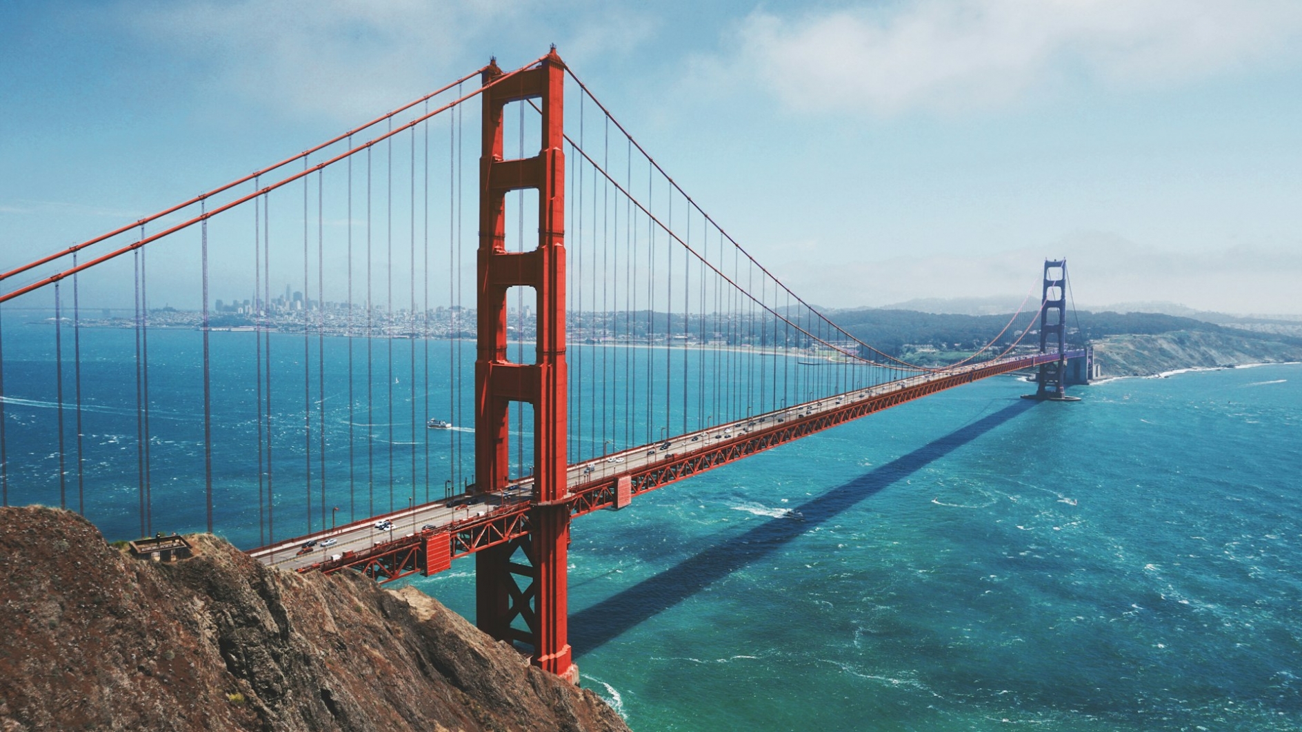 Photo of the Golden Gate bridge, stretching into the distance, over blue water