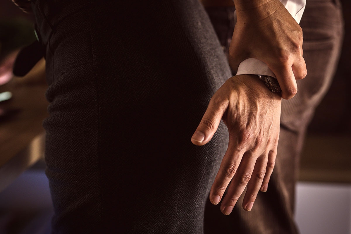 A woman grabs a man's arm as he tries to put his hand on her butt