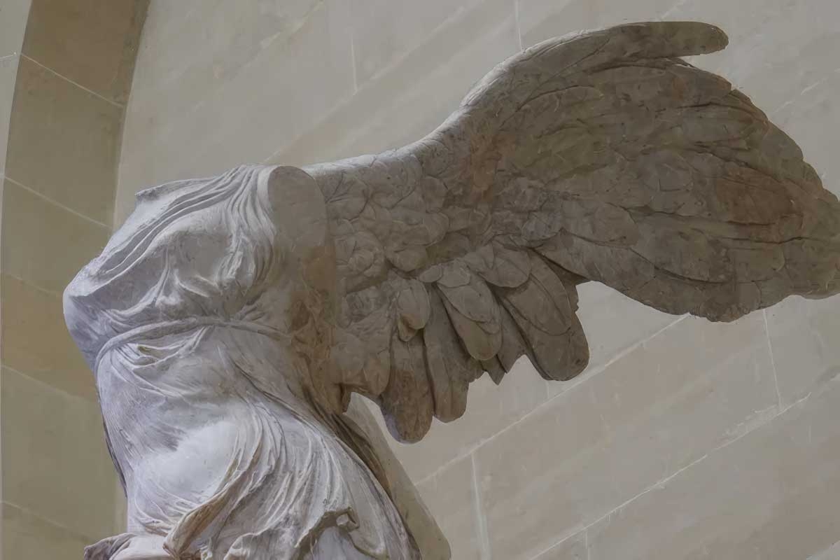 marble statue of a winged woman who's missing her head