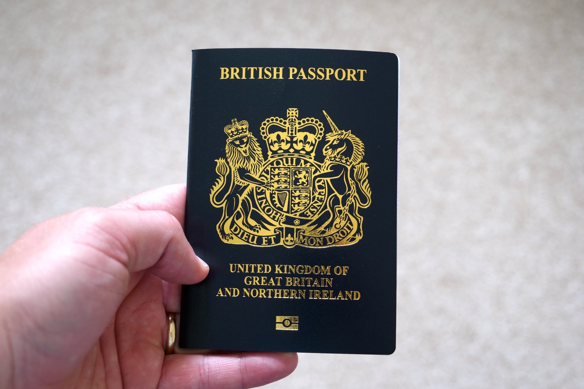 A man's hand, holding a British passport