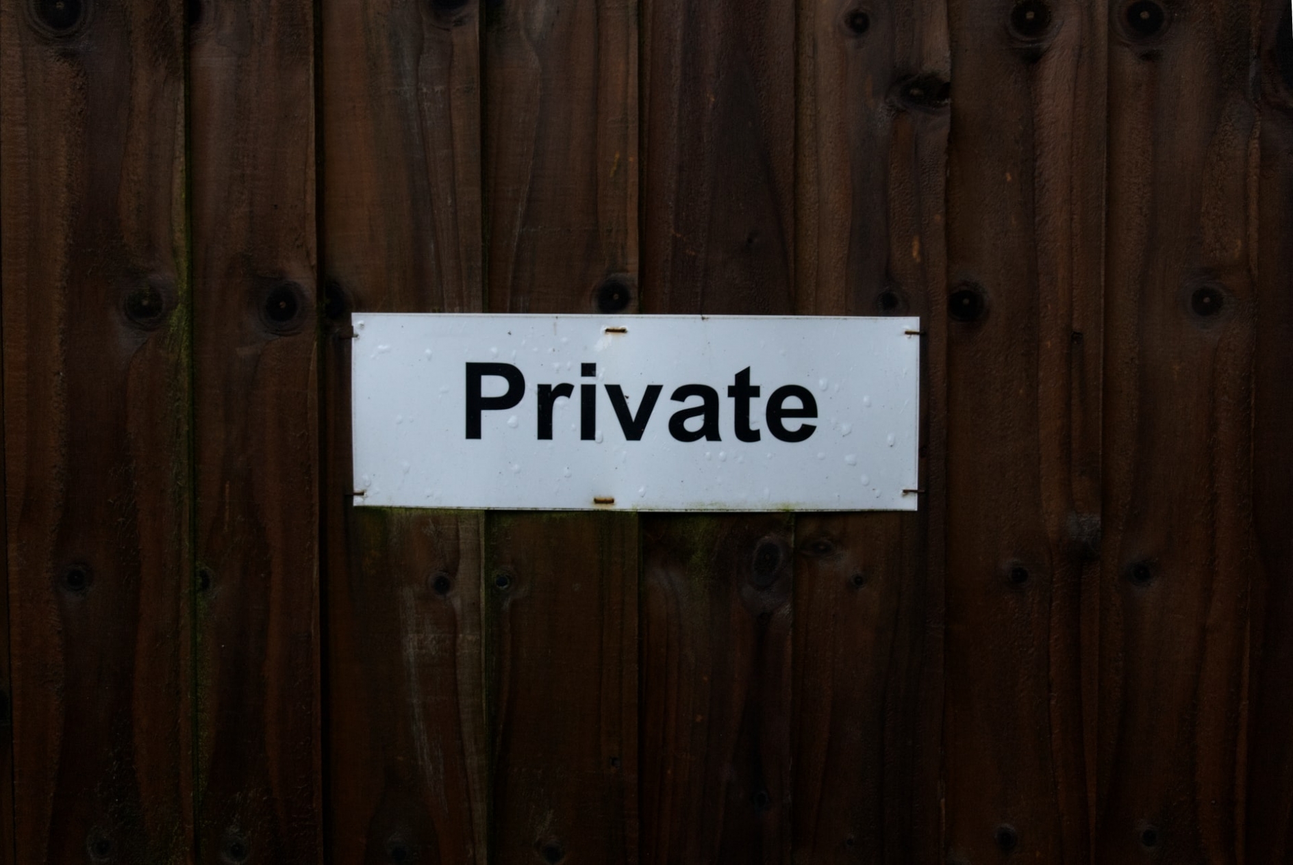 Small sign stapled to a wooden wall that reads Private