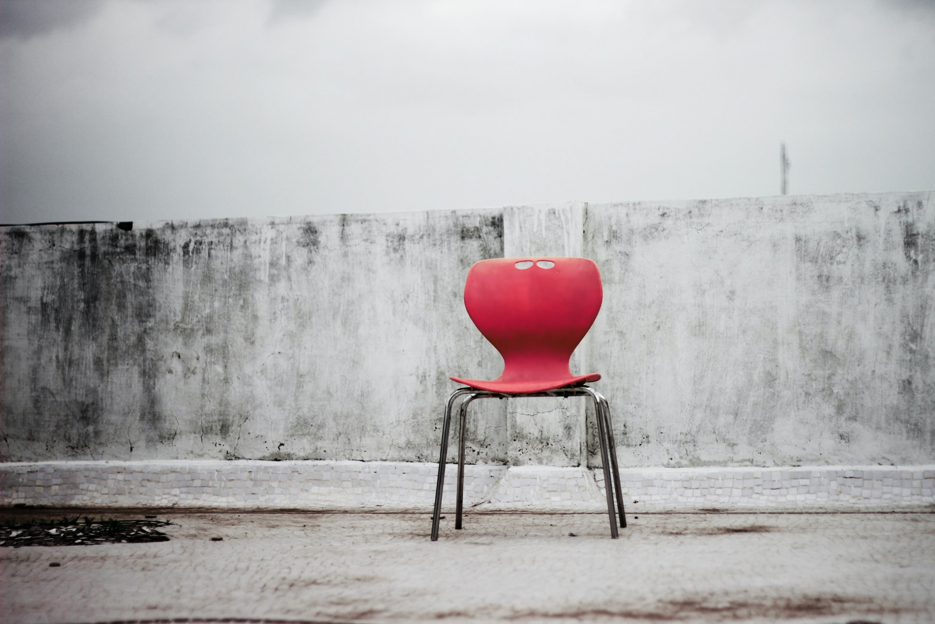 Red chair on a tile floor, in front of a plain stucco wall
