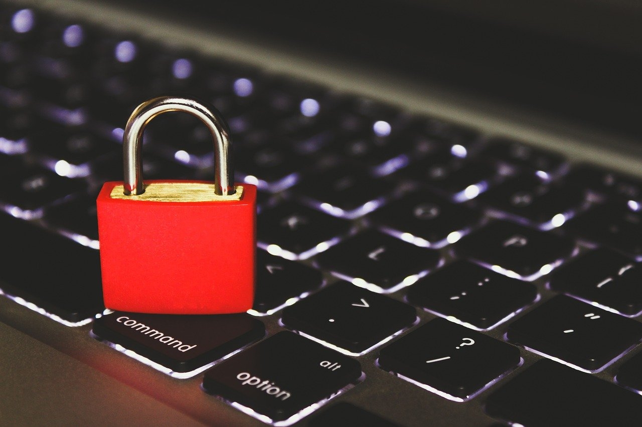 A red padlock sitting on the keyboard of a notebook computer