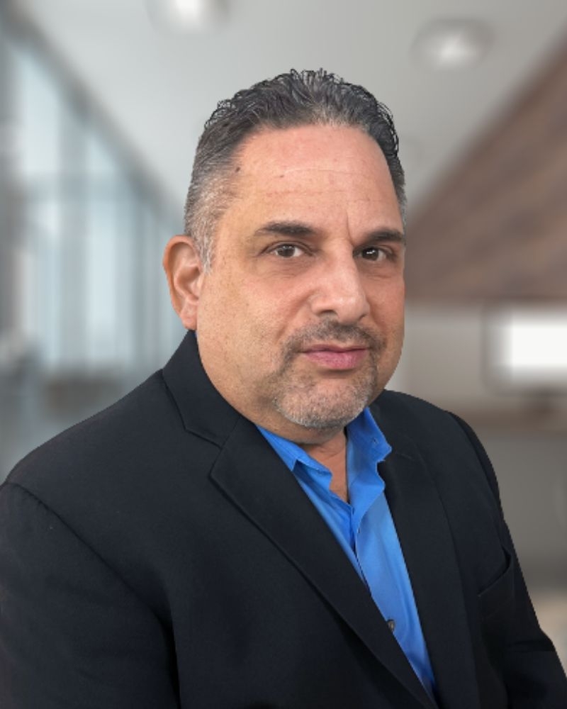 Headshot of a middle-age man wearing a blue shirt and black sports coat