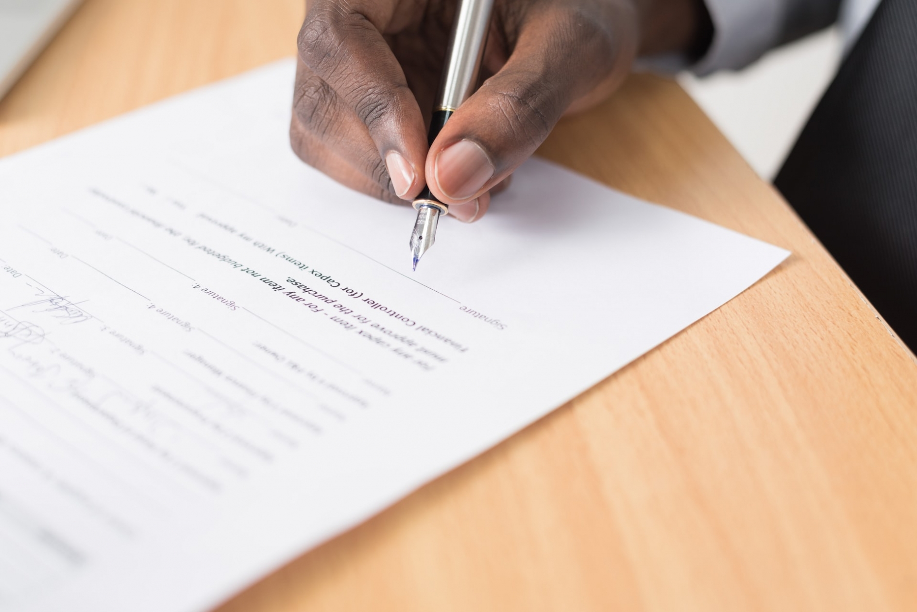 closeup photo of a black man's hand, signing a contract