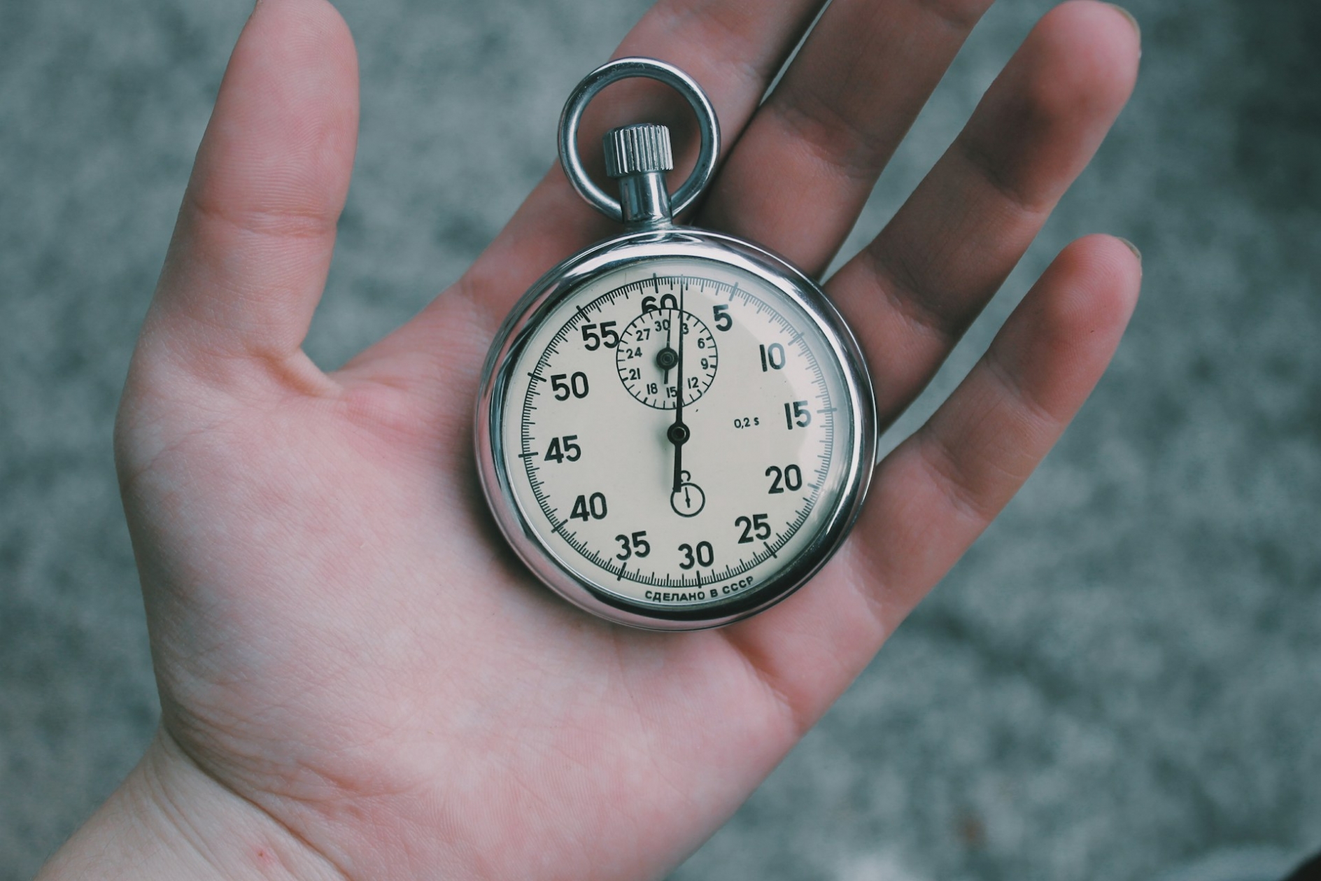 A man's hand, holding a stopwatch.