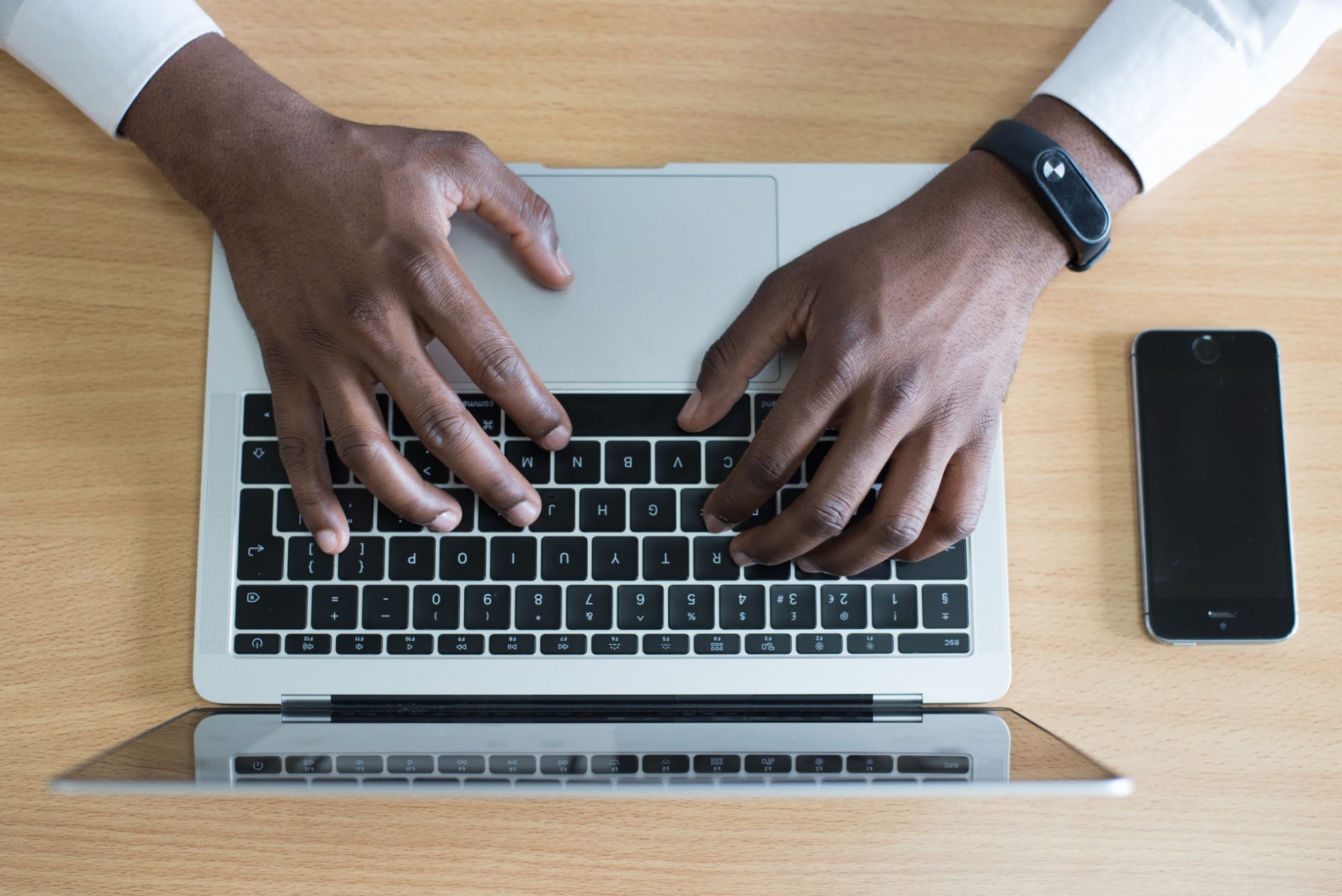 the hands of a black man typing on a notebook computer
