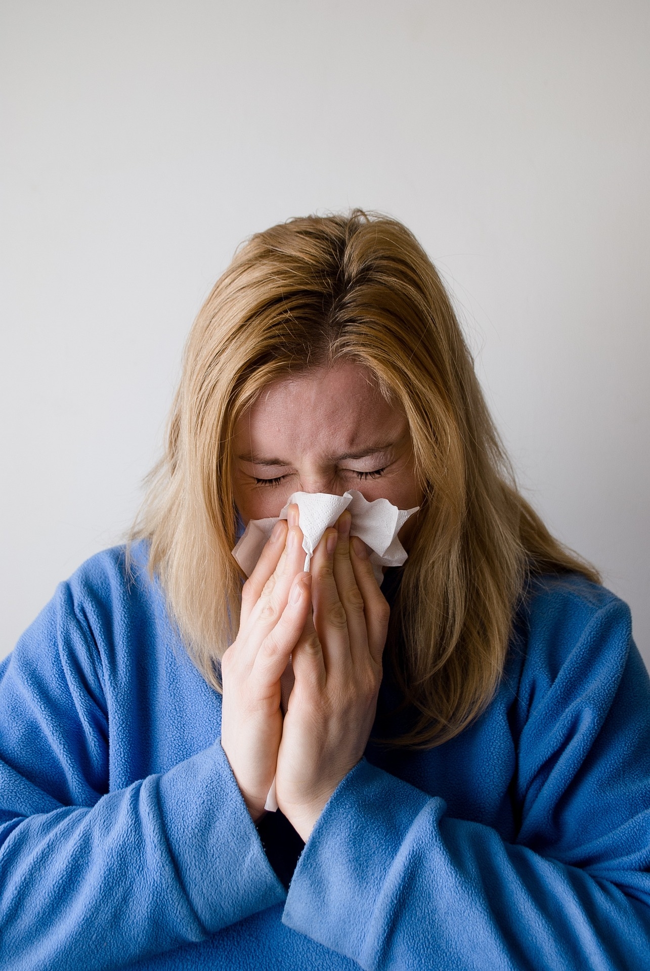 A woman blowing her nose into a tissue