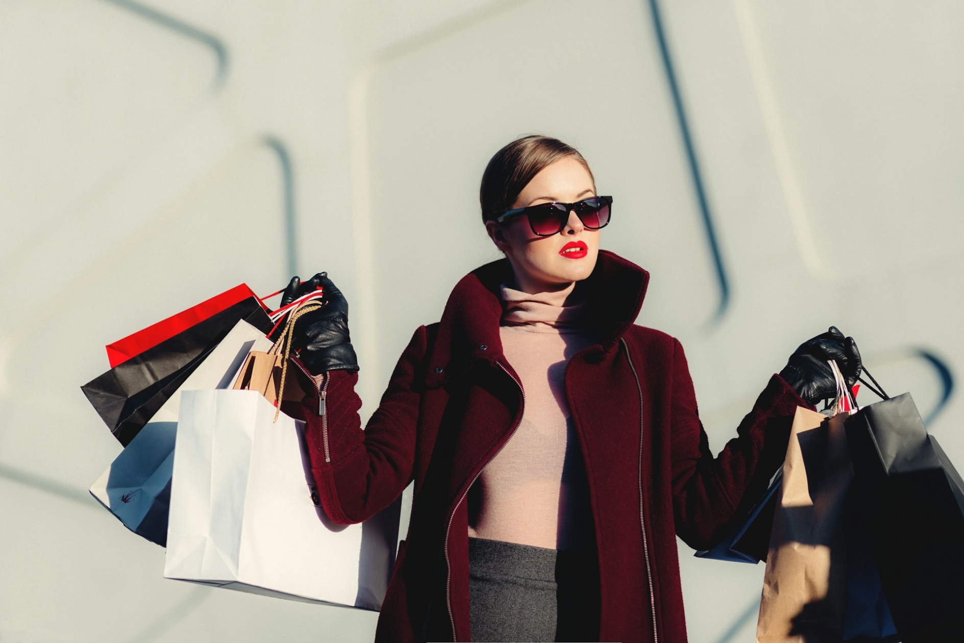 Woman wearing designer clothes and sunglasses, carrying shopping bags