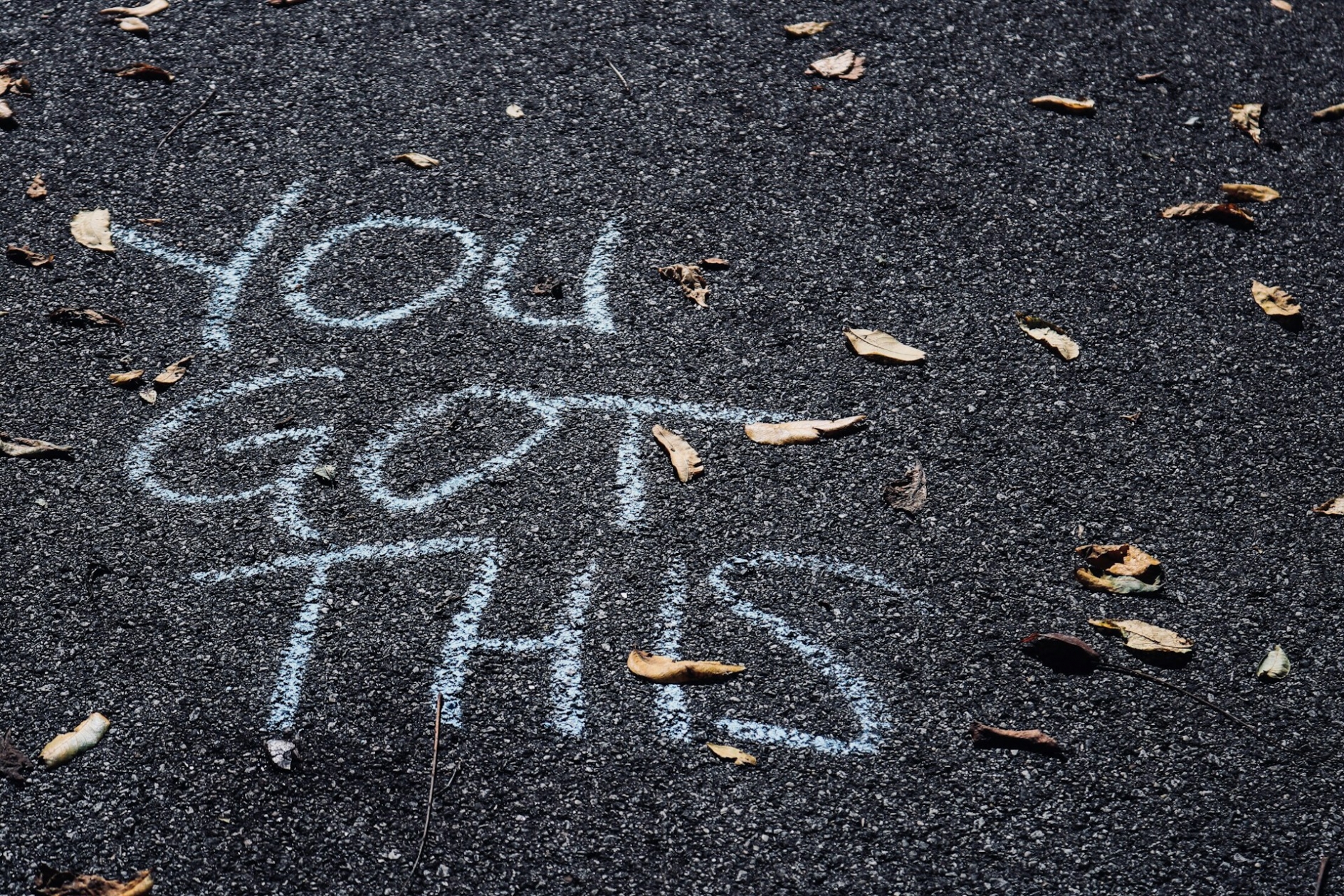The words "You Got This" written in chalk on black pavement